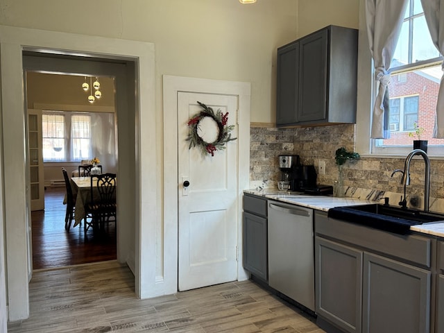 kitchen with gray cabinetry, dishwasher, sink, and light hardwood / wood-style flooring