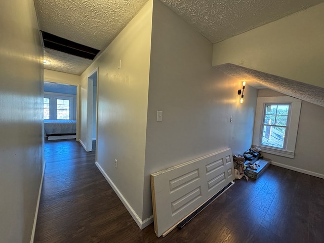 hall with a textured ceiling, dark hardwood / wood-style floors, and lofted ceiling