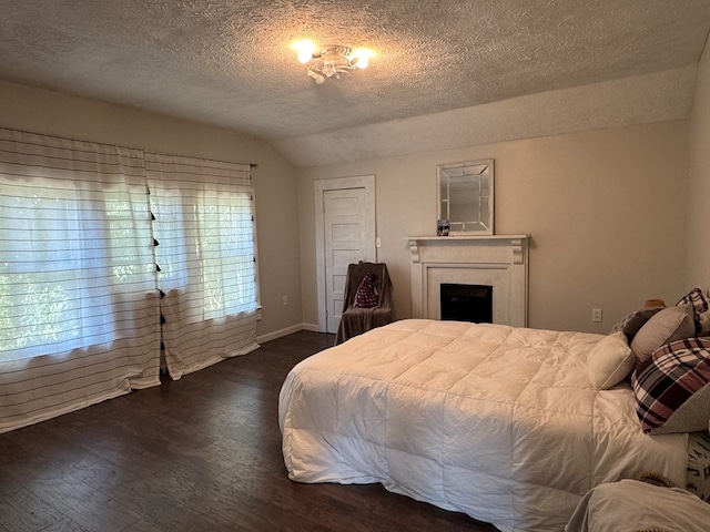 bedroom with a textured ceiling, vaulted ceiling, and dark hardwood / wood-style floors