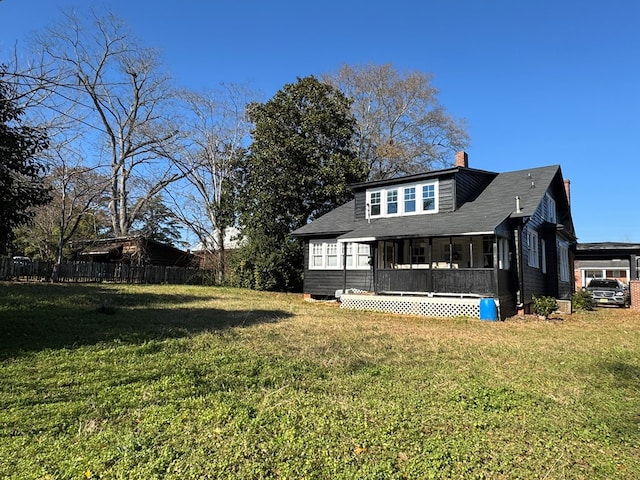 back of property with a sunroom and a yard