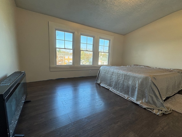 bedroom with dark hardwood / wood-style flooring and a textured ceiling