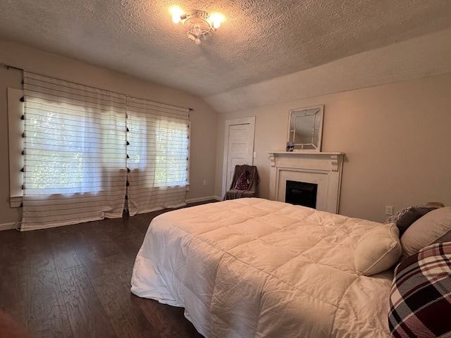 bedroom with a textured ceiling, lofted ceiling, and dark wood-type flooring