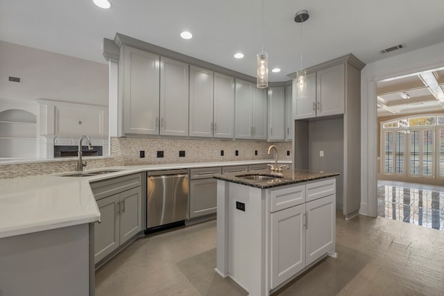 kitchen with stainless steel dishwasher, dark stone countertops, a center island with sink, and sink