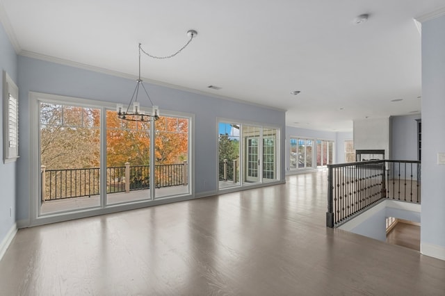 interior space featuring a large fireplace, hardwood / wood-style flooring, ornamental molding, and a chandelier