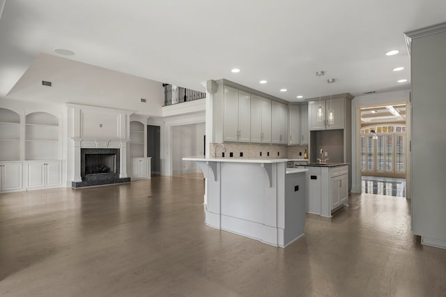 kitchen with decorative light fixtures, a premium fireplace, backsplash, built in features, and a kitchen breakfast bar