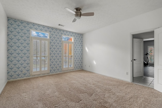 carpeted spare room featuring ceiling fan and a textured ceiling