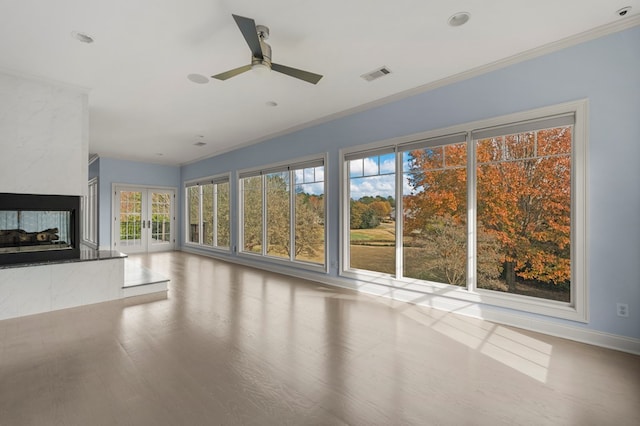 unfurnished living room featuring ceiling fan, crown molding, french doors, and a wealth of natural light