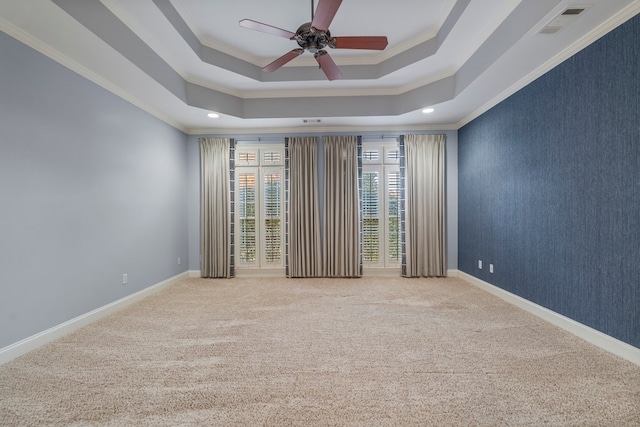 carpeted empty room with ceiling fan, ornamental molding, and a tray ceiling