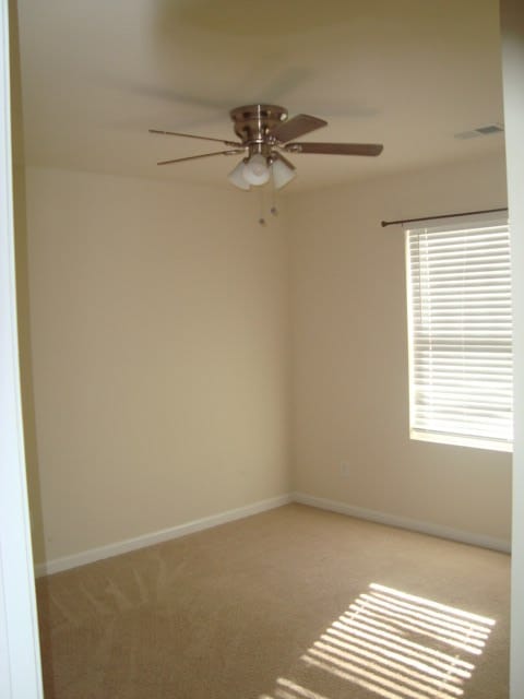 carpeted empty room featuring ceiling fan