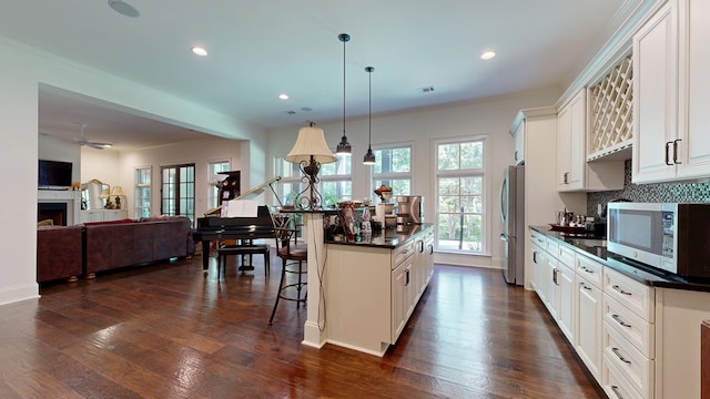 7718 River Crest Dr, Columbus, GA 31904 - kitchen featuring appliances with stainless steel finishes, dark countertops, a kitchen bar, a kitchen island, and hanging light fixtures