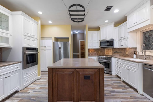 175 Slaughter Dr, Waverly Hall, GA 31831 - kitchen with stainless steel appliances, light wood finished floors, tasteful backsplash, a center island, and white cabinetry