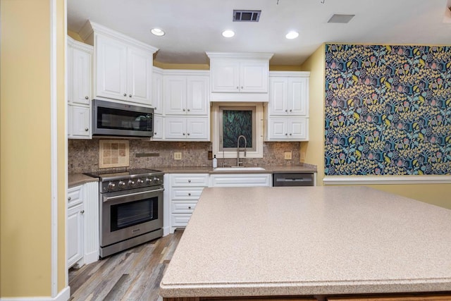 175 Slaughter Dr, Waverly Hall, GA 31831 - kitchen with stainless steel appliances, white cabinets, wood finished floors, decorative backsplash, and recessed lighting