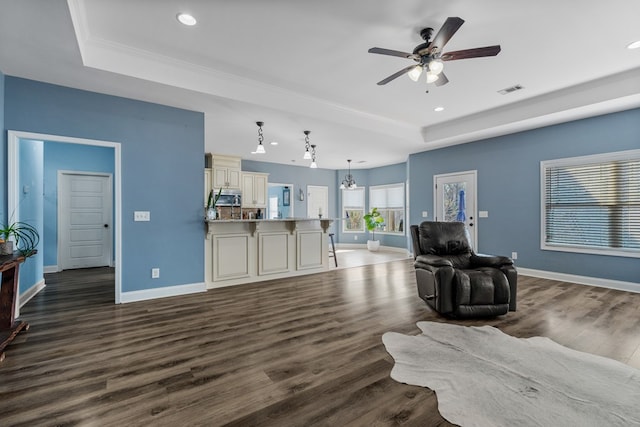 living room with dark wood finished floors, a tray ceiling, baseboards, and visible vents