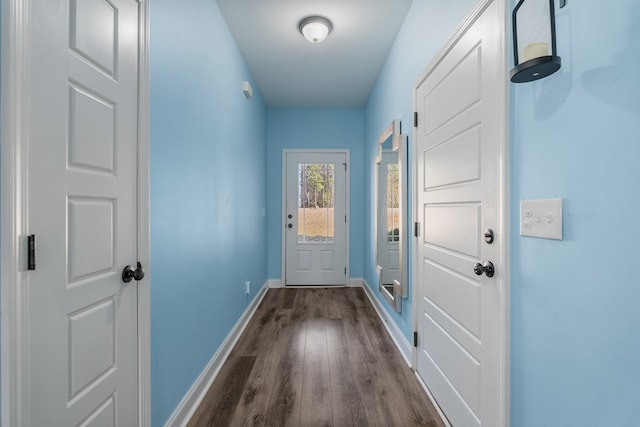 doorway to outside featuring baseboards and dark wood-style flooring