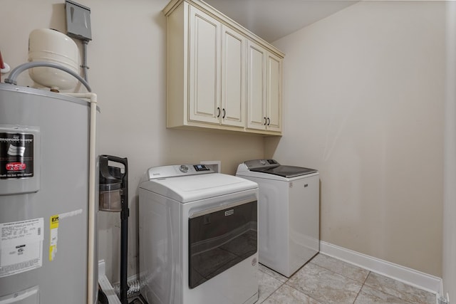 laundry area with independent washer and dryer, water heater, cabinet space, light tile patterned floors, and baseboards