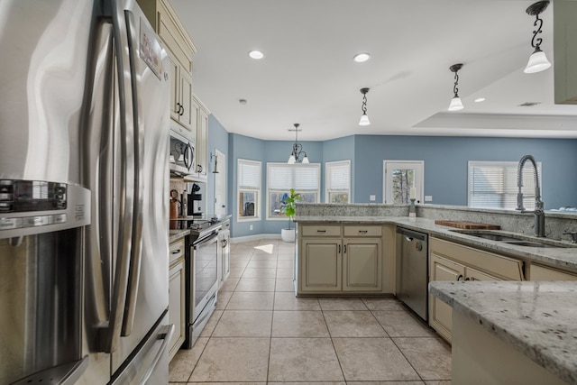 kitchen featuring light tile patterned floors, a sink, appliances with stainless steel finishes, cream cabinets, and decorative light fixtures