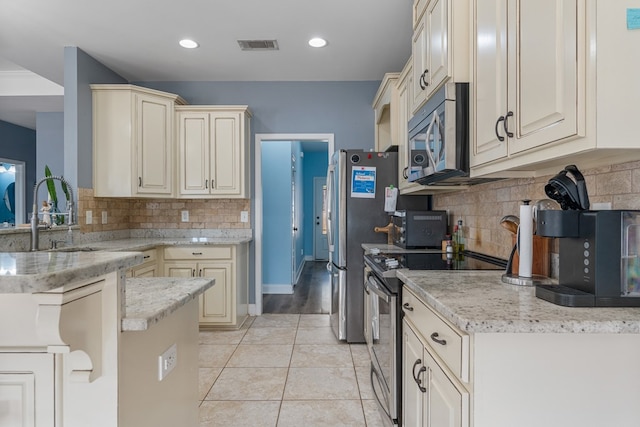 kitchen featuring cream cabinetry, visible vents, light tile patterned floors, and stainless steel appliances