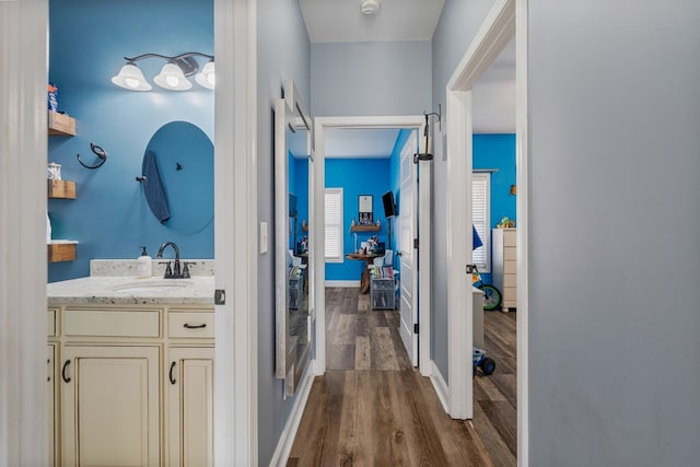 hall with a sink, baseboards, and dark wood-type flooring