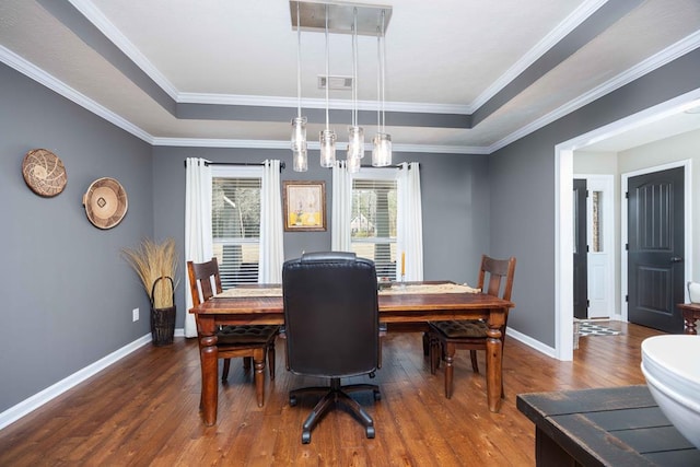 dining space featuring baseboards, visible vents, a tray ceiling, and wood finished floors