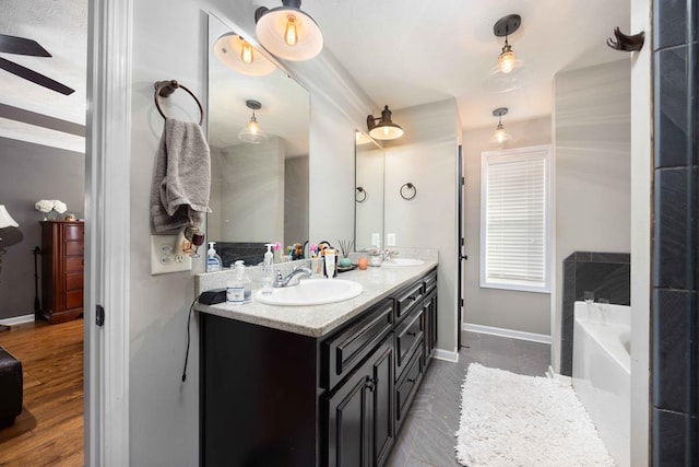 full bathroom featuring double vanity, a sink, a bath, and baseboards