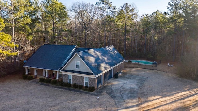 view of front facade with a wooded view and dirt driveway