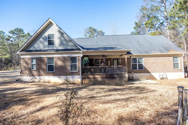 back of property with ceiling fan, brick siding, and roof with shingles