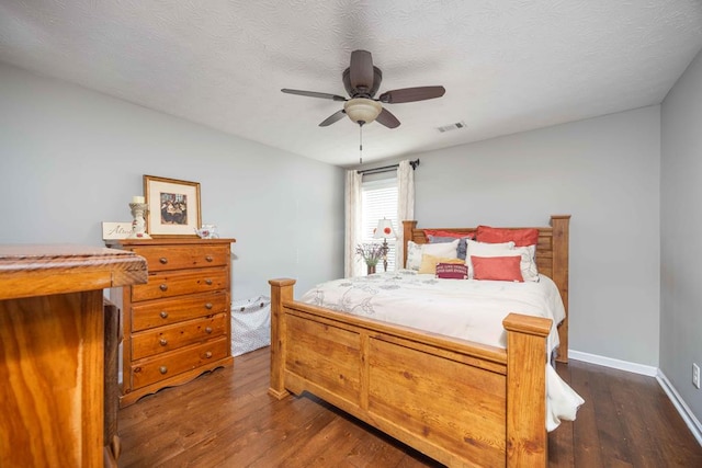 bedroom featuring dark wood-style floors, visible vents, a textured ceiling, and baseboards