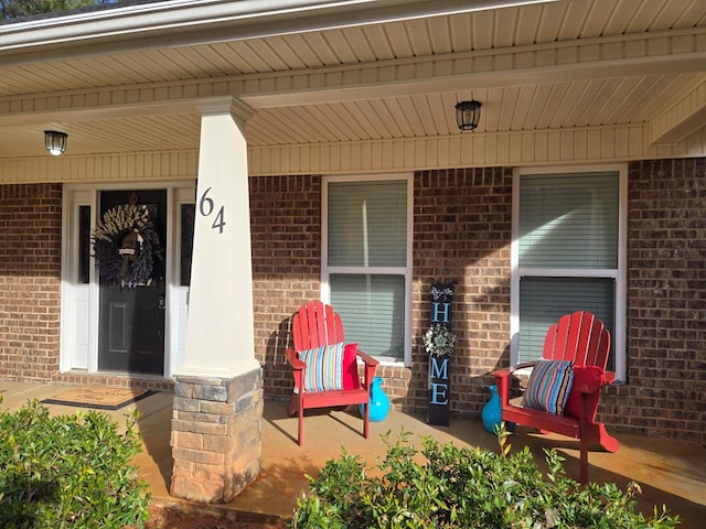 doorway to property featuring a porch and brick siding