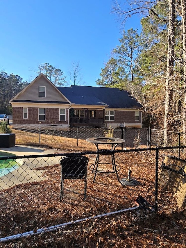 rear view of house featuring brick siding and fence