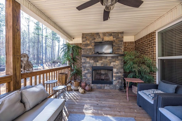 wooden terrace with an outdoor living space with a fireplace and ceiling fan