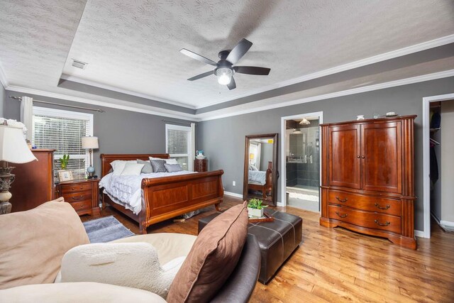 bedroom with light wood finished floors, baseboards, a raised ceiling, crown molding, and a textured ceiling