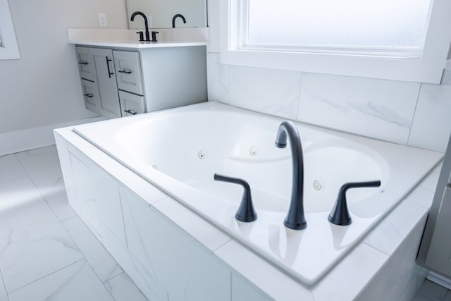 bathroom with vanity and tiled tub