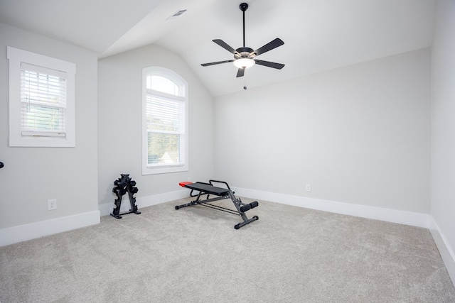 exercise room featuring ceiling fan, light colored carpet, and vaulted ceiling