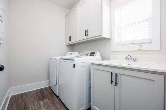 laundry area featuring washing machine and clothes dryer, dark hardwood / wood-style flooring, sink, and cabinets