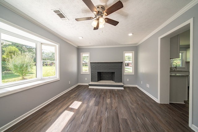 unfurnished living room featuring a brick fireplace, ornamental molding, a textured ceiling, ceiling fan, and dark hardwood / wood-style floors