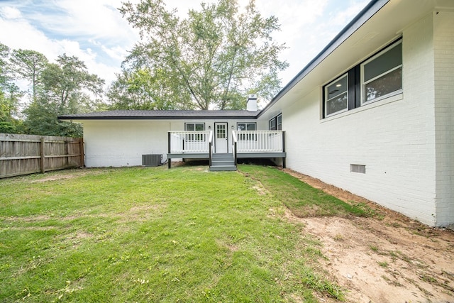 rear view of house featuring central AC unit, a yard, and a wooden deck