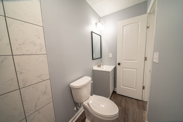 bathroom with vanity, a textured ceiling, hardwood / wood-style flooring, and toilet