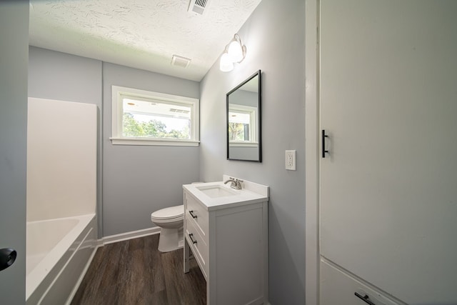 bathroom with vanity, wood-type flooring, a textured ceiling, and toilet