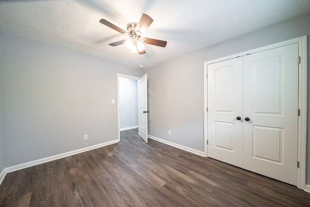 unfurnished bedroom with a textured ceiling, dark hardwood / wood-style flooring, a closet, and ceiling fan