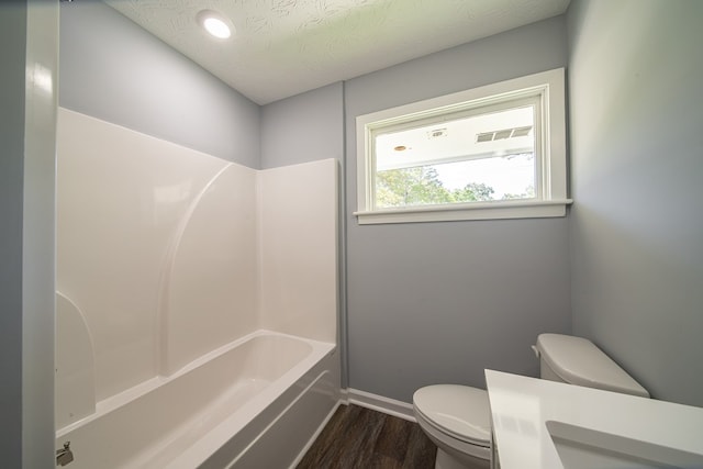 bathroom with shower / bathing tub combination, a textured ceiling, hardwood / wood-style flooring, and toilet