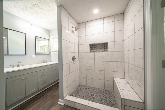 bathroom featuring vanity, hardwood / wood-style floors, a textured ceiling, and a tile shower