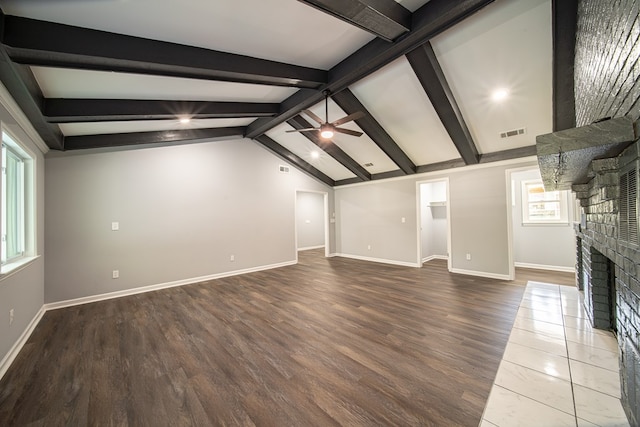 unfurnished living room with lofted ceiling with beams, wood-type flooring, a wealth of natural light, and a brick fireplace