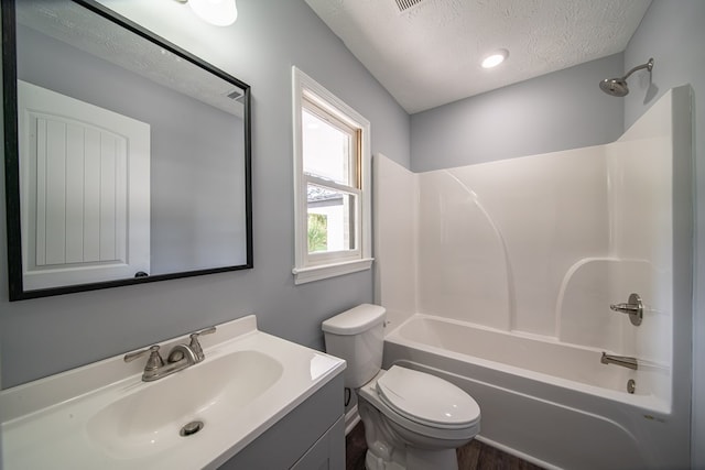 full bathroom with vanity,  shower combination, toilet, and a textured ceiling