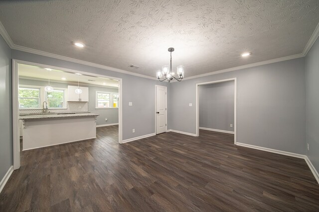 unfurnished dining area with a chandelier, a textured ceiling, dark hardwood / wood-style floors, and ornamental molding