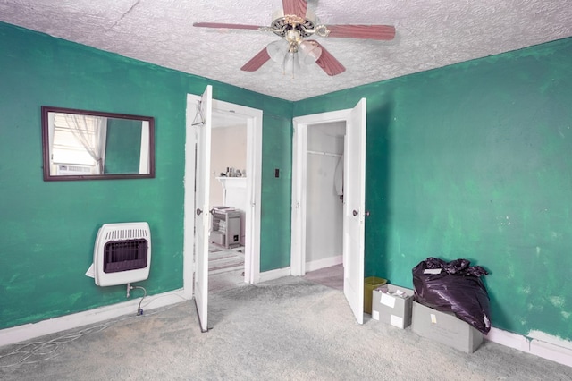 bedroom featuring a ceiling fan, a textured ceiling, baseboards, heating unit, and carpet