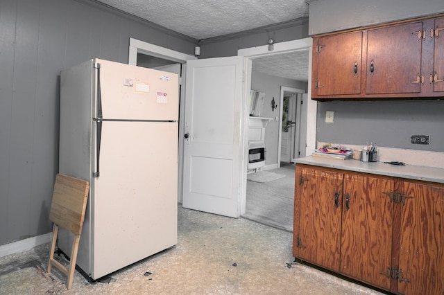 kitchen featuring freestanding refrigerator, a textured ceiling, brown cabinets, and light countertops