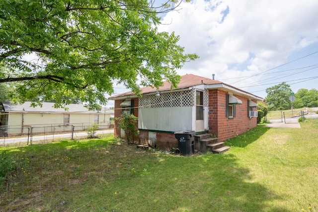 view of side of property with brick siding, fence, a yard, and entry steps