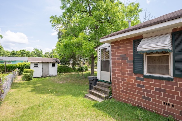 view of yard featuring fence, an outdoor structure, entry steps, and a storage unit