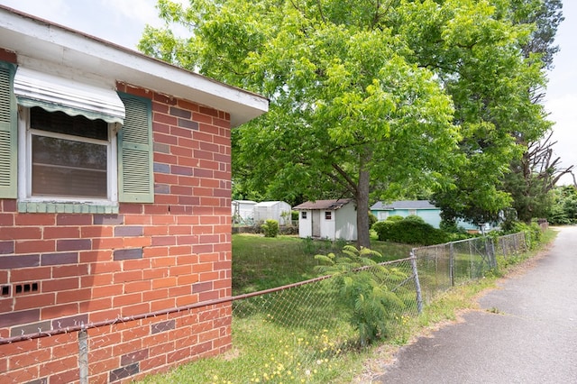 view of side of home with brick siding, an outdoor structure, fence, and a storage unit