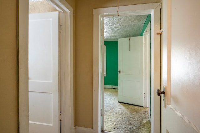 corridor with a textured ceiling and carpet